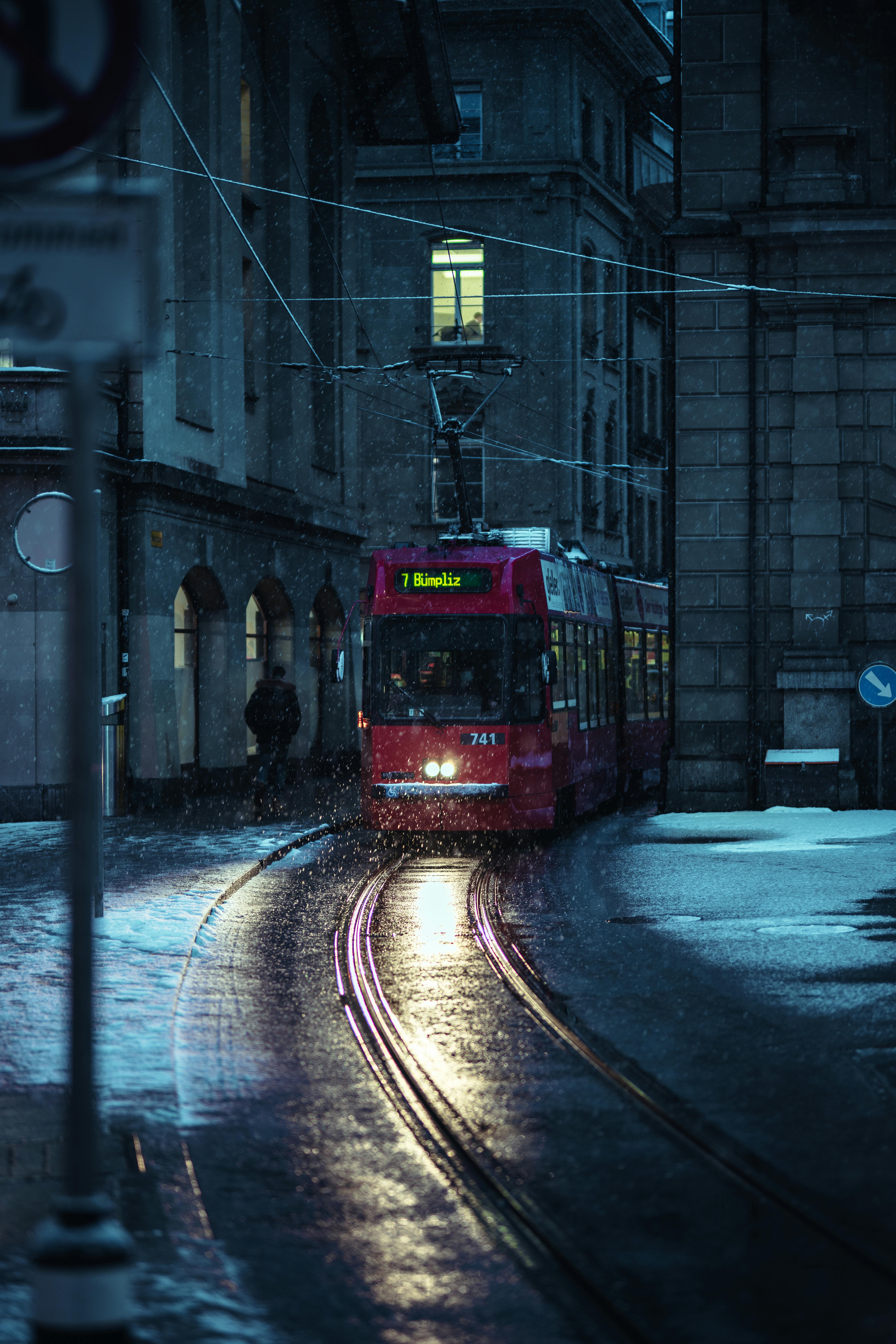 Free A vibrant tram travels on wet streets during a rainy night in Bern, Switzerland. Stock Photo