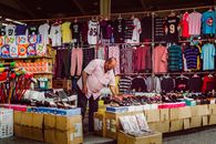 A vendor arranges shoes at a vibrant street market in Kuwait City, highlighting local commerce.