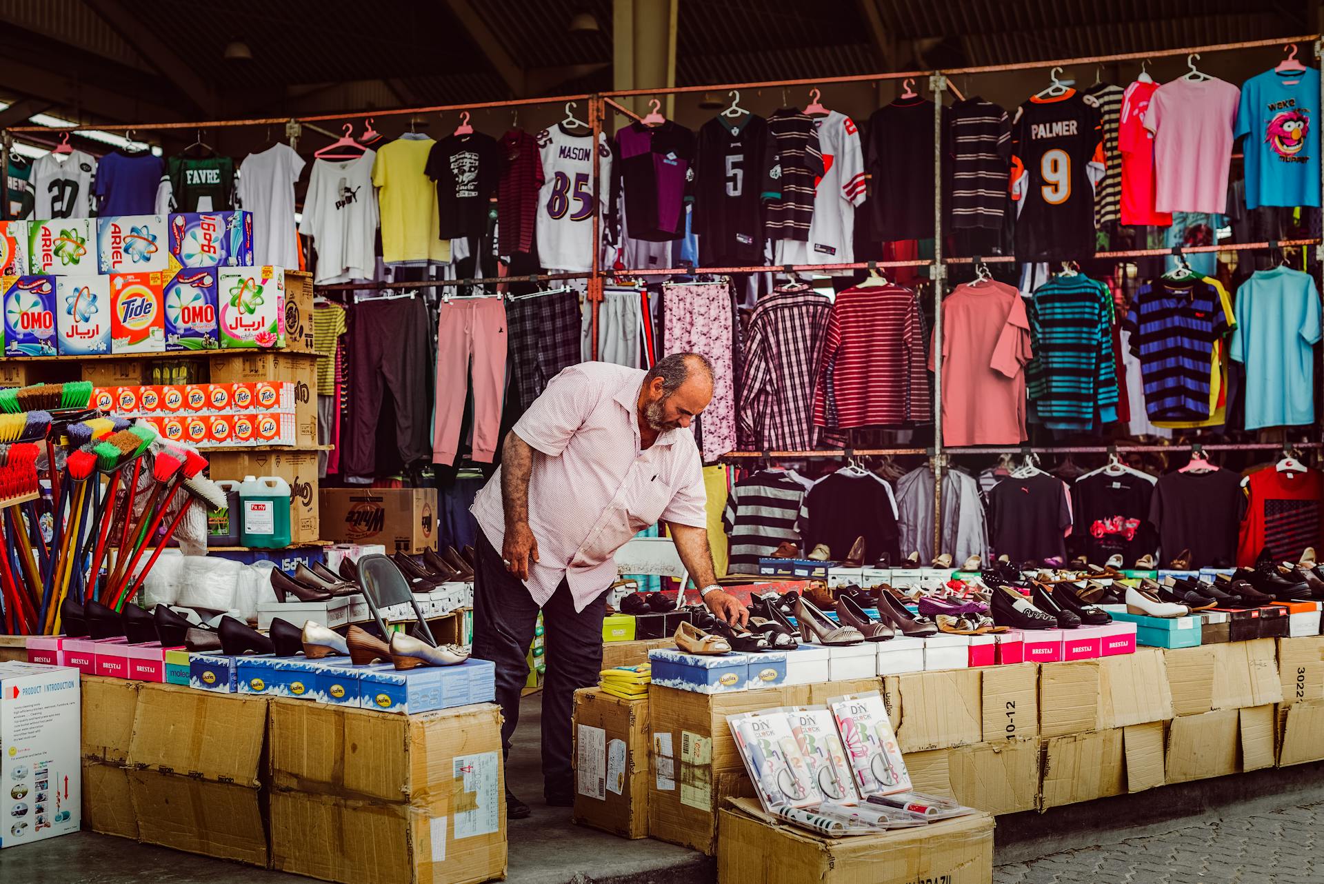 A vendor arranges shoes at a vibrant street market in Kuwait City, highlighting local commerce.