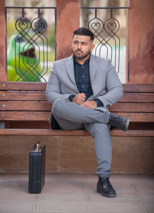 Free Confident businessman in gray suit sitting on a bench in Tehran, exuding style and professionalism. Stock Photo