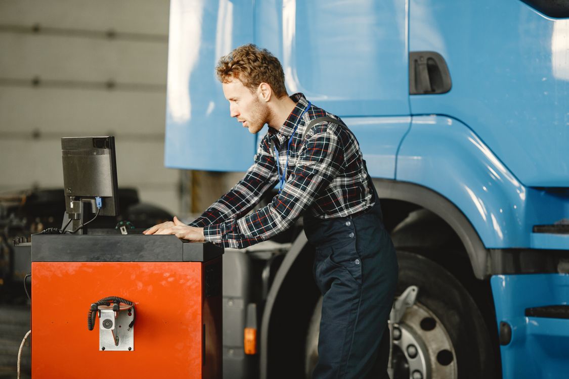 Diesel technician using a computer to diagnose a large truck