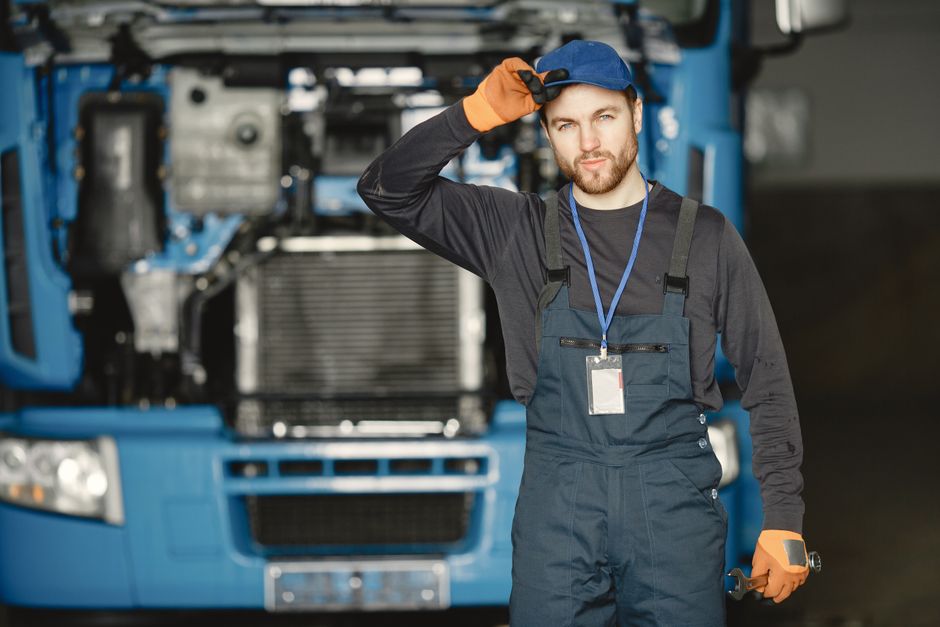 Local HVAC Expert - Long Beach — Auto mechanic in uniform poses confidently with truck in background.