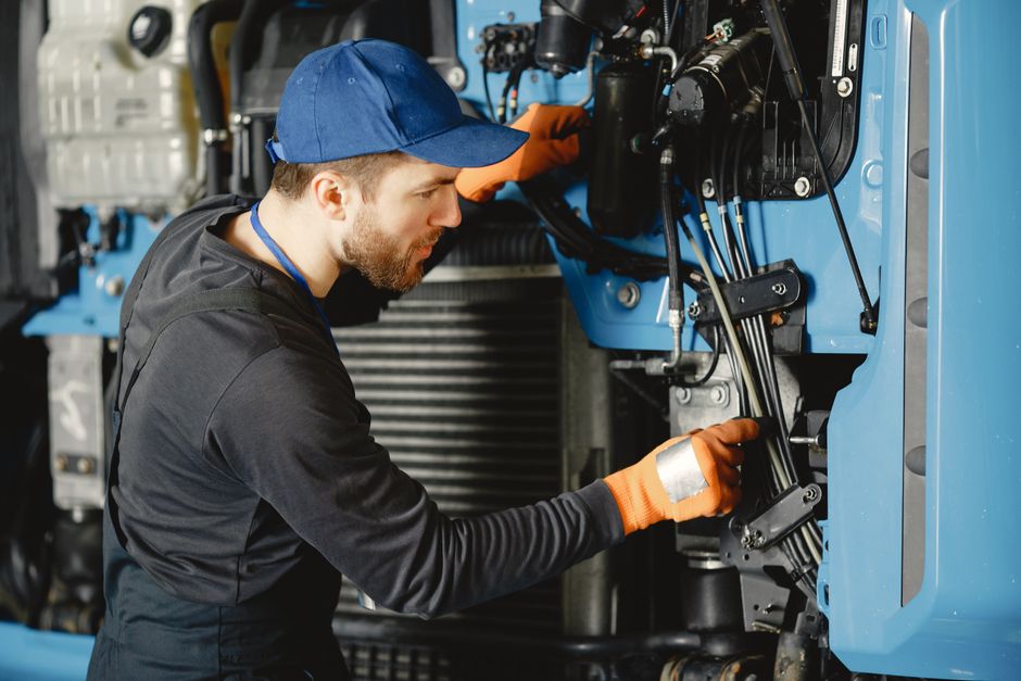 Skilled worker in safety gear repairing industrial equipment.