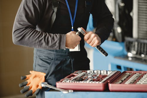Free Man in Black Jumper and Overall Holding Metal Wrench Above the Toolbox Stock Photo