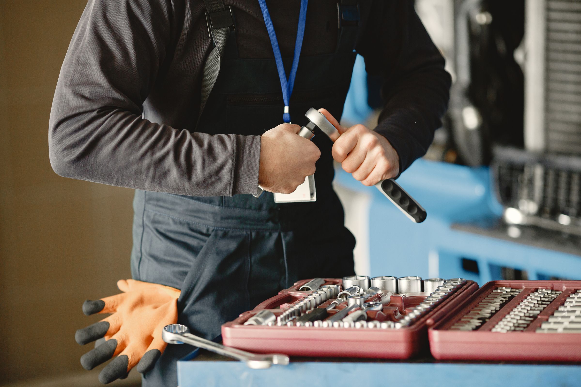 Mechanic in a garage selecting a socket from a red socket set to use with a torque wrench on a vehicle