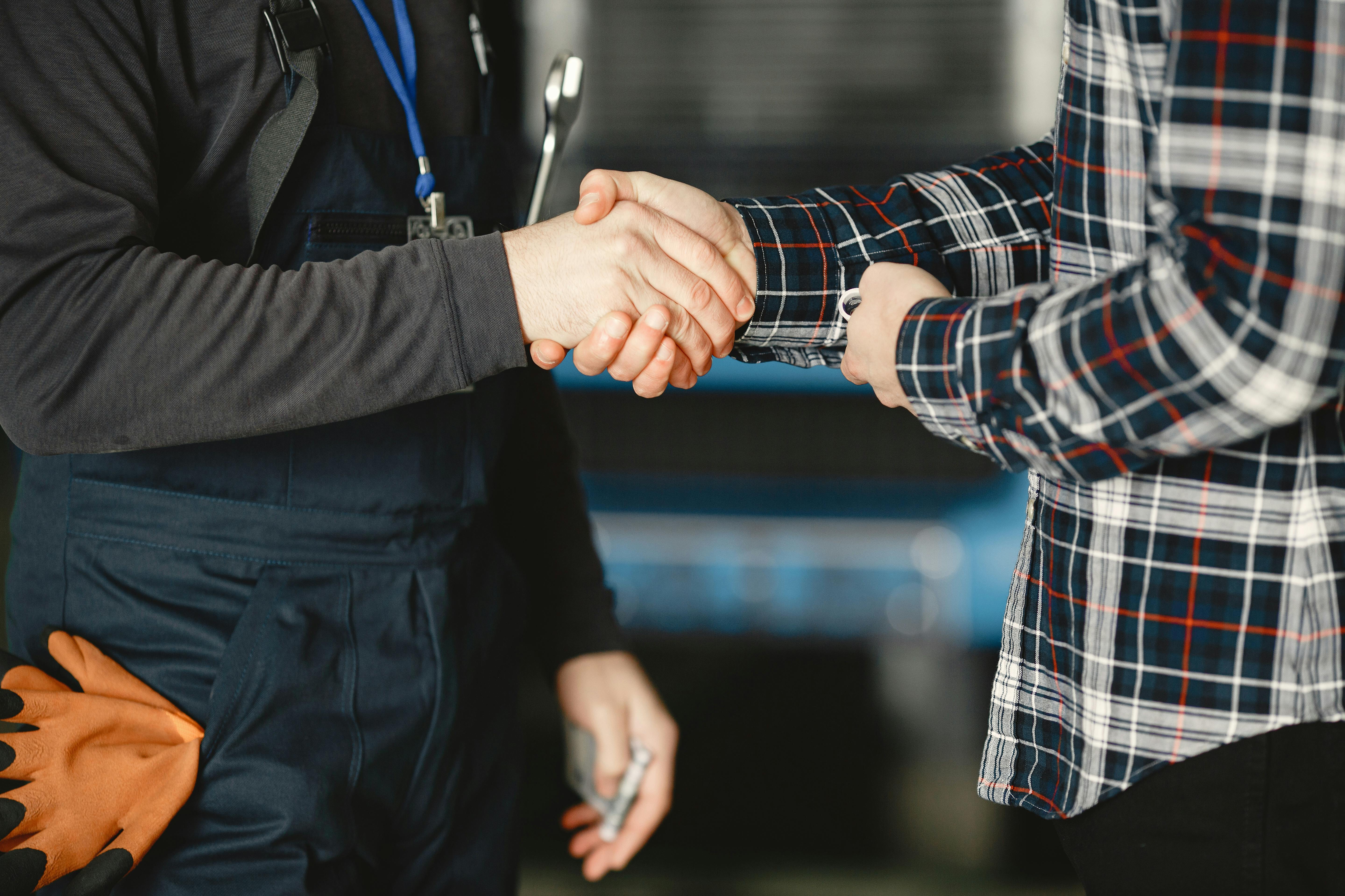 Close-up of a handshake between workers in a workshop, symbolizing business agreement and teamwork.