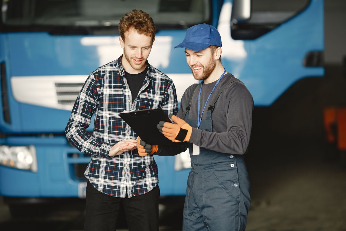 Two mechanics reviewing documentation and a folder together