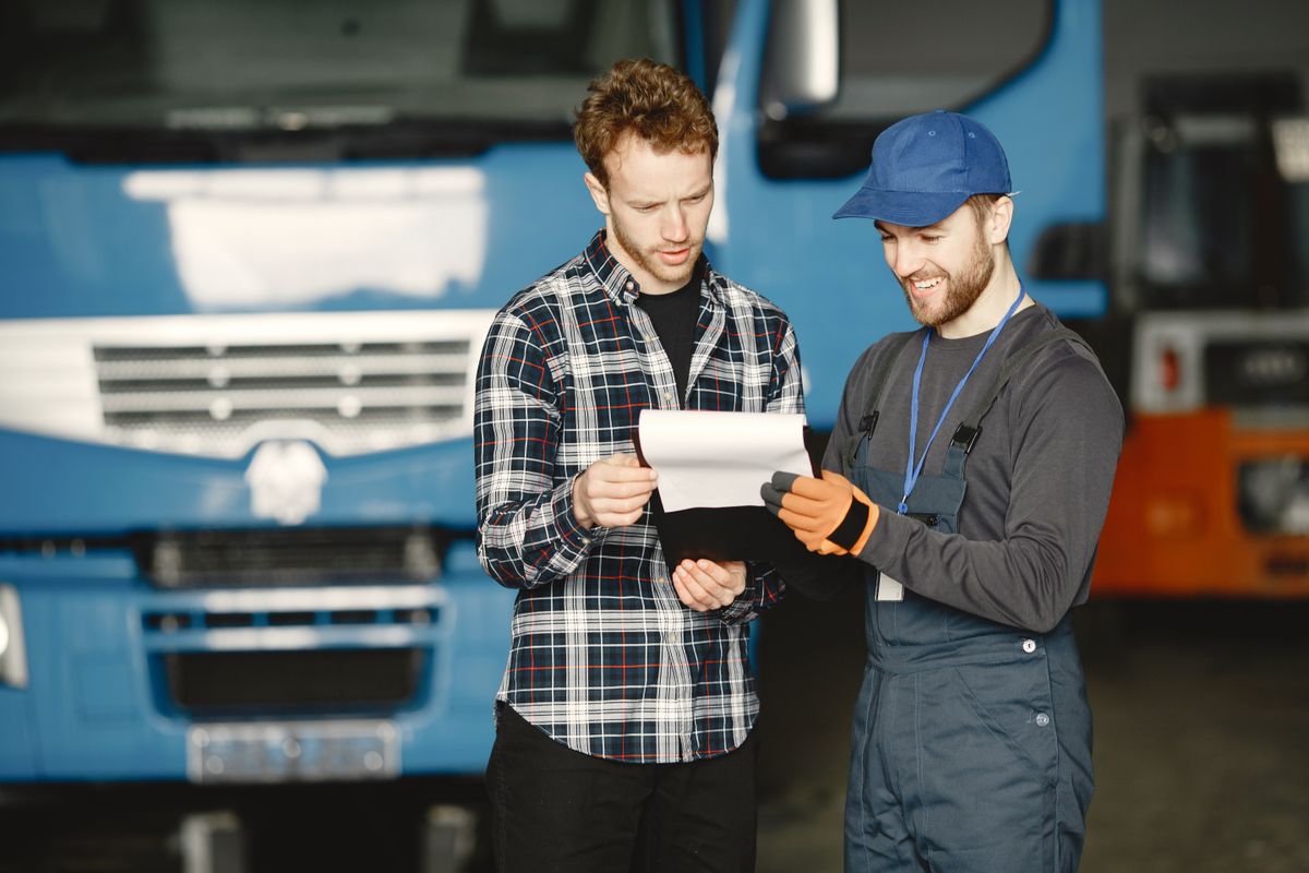 A mechanic and a customer discussing repair paperwork in a truck garage