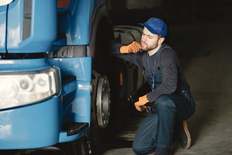 Worker In Blue Cap Sitting Beside Blue Truck Thinking