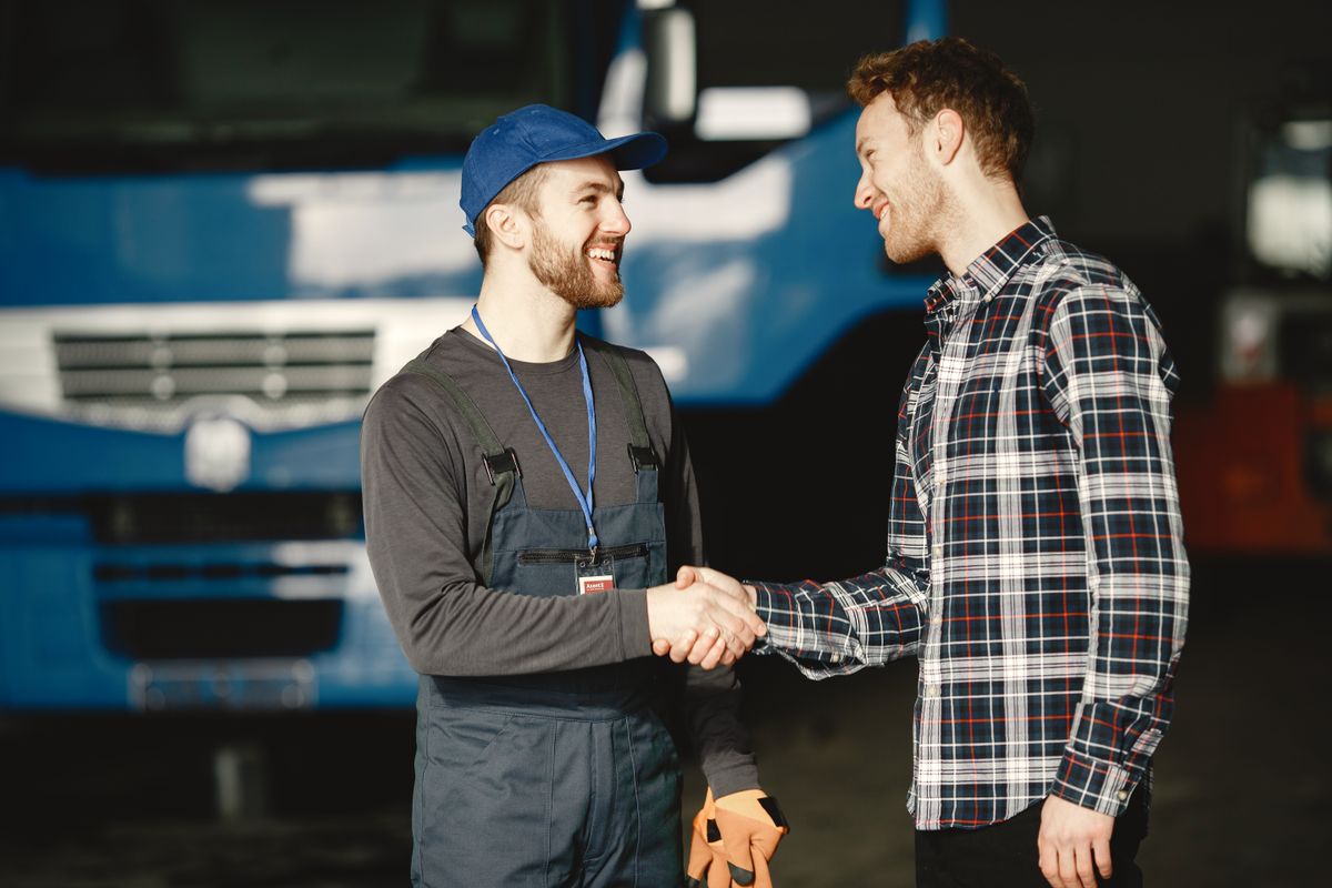 A mechanic and a customer shaking hands after a job is completed