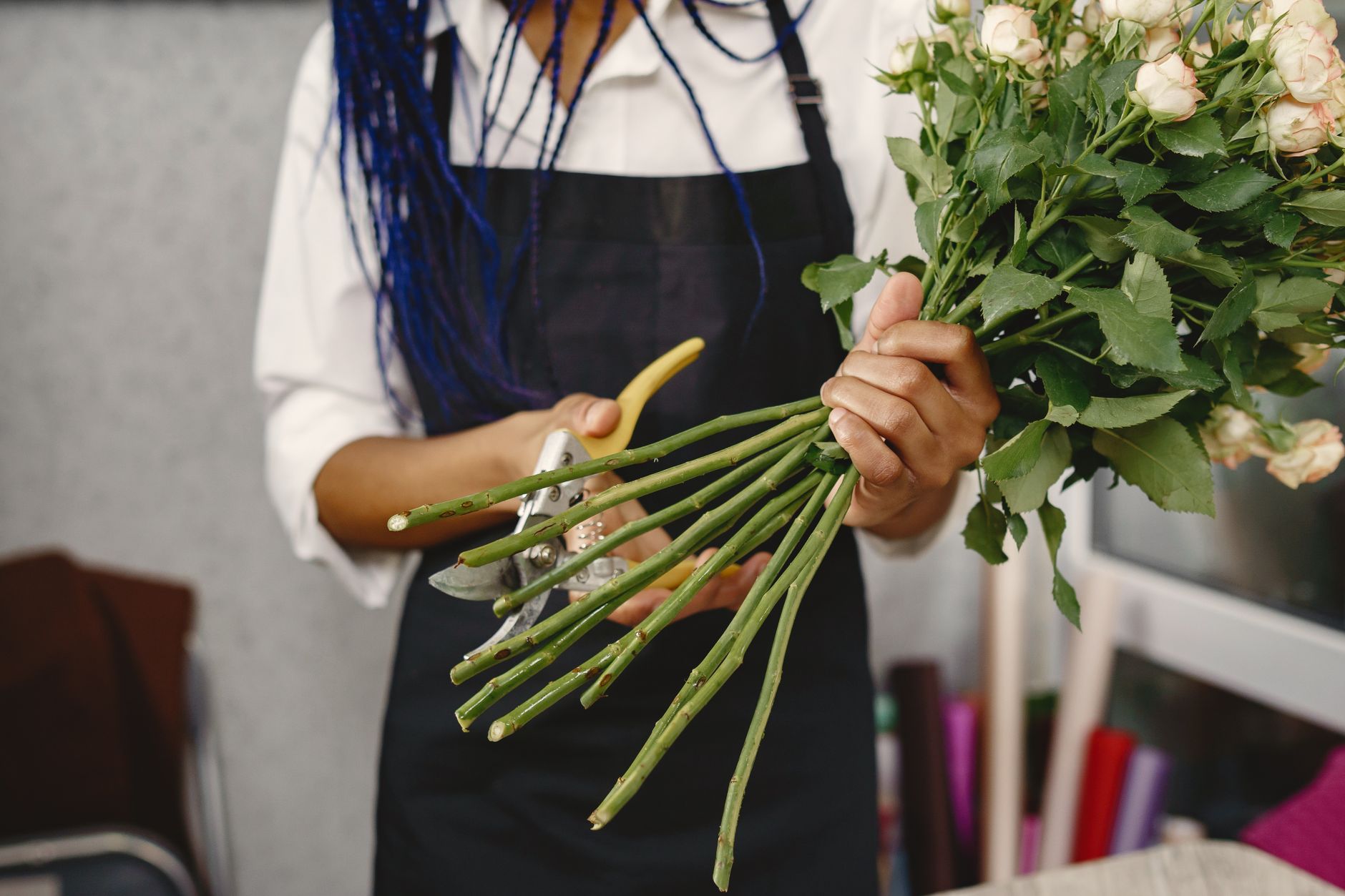 A florist skillfully trims rose stems to create a beautiful bouquet indoors.