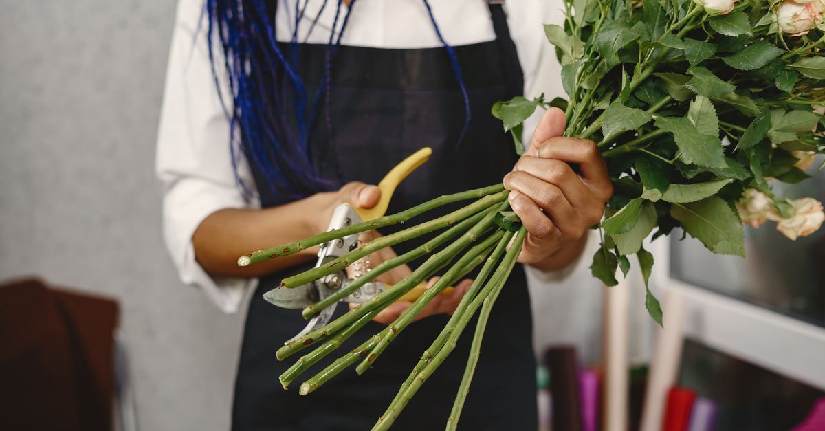 Step-by-step flower care: florist cutting rose stem at 45 degrees angle for optimal water absorption.