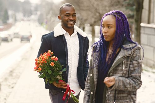 Free A couple strolling outdoors with a bouquet of flowers, sharing a moment of love. Stock Photo
