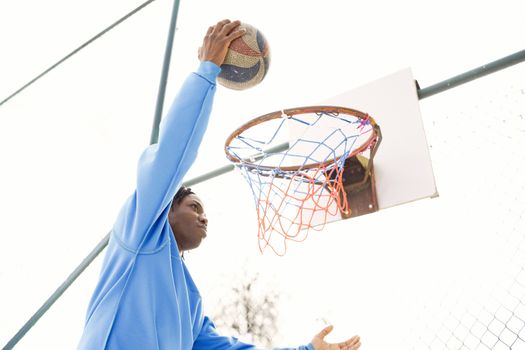 A young athlete performs a slam dunk on an outdoor basketball court, showcasing agility and skill.