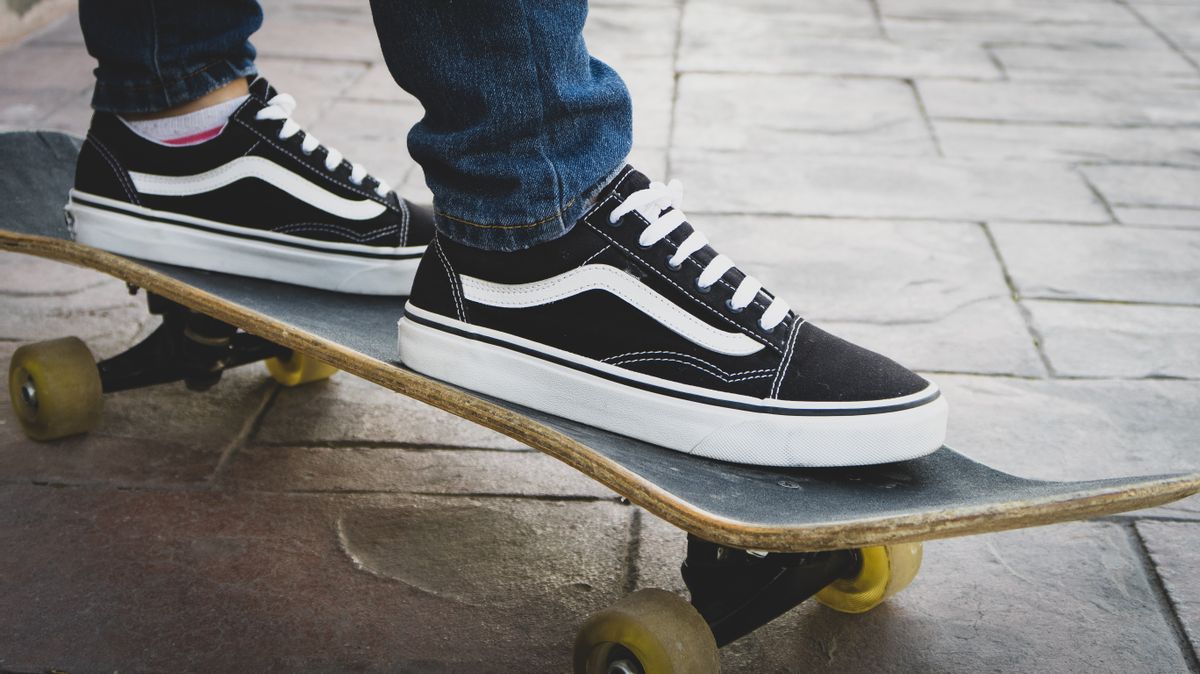A pair of classic black and white vulcanized skate shoes standing on a skateboard.