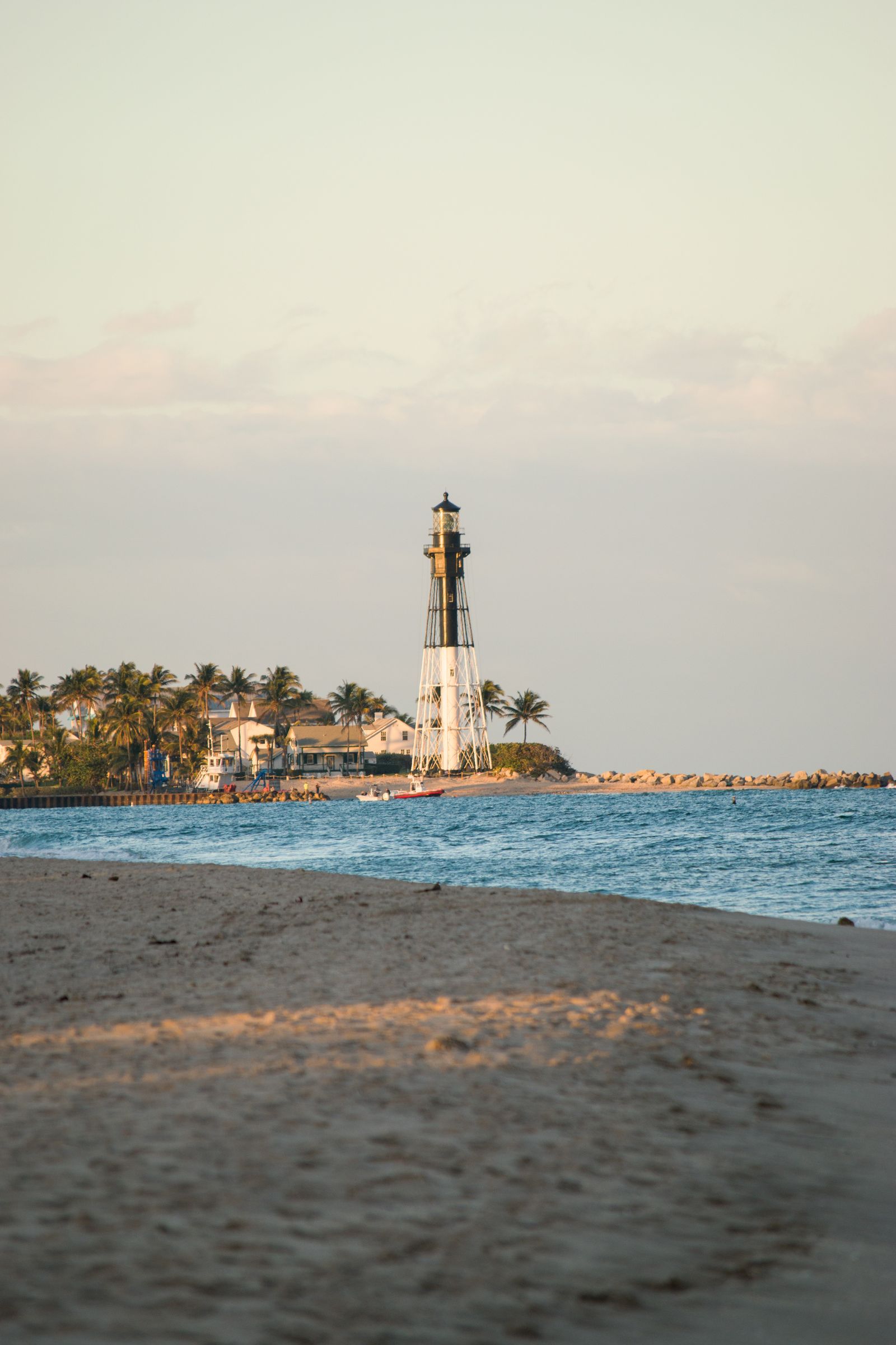 Lighthouse along a sandy beach with calm ocean waters