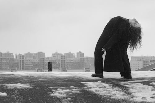 A Woman in Black Coat Bending Backwards at the Rooftop