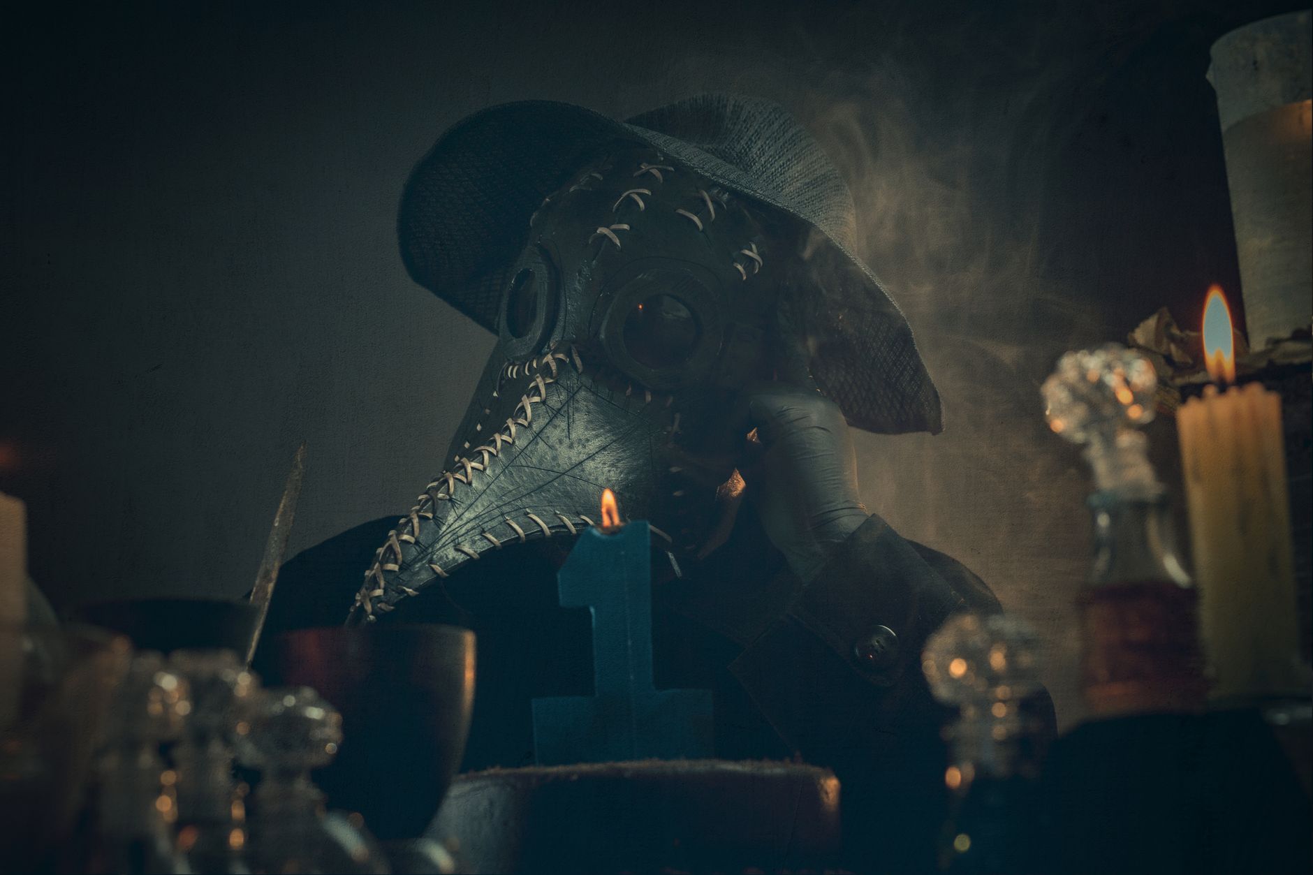 A mysterious figure in a plague doctor mask amidst candlelight and smoke, creating an eerie atmosphere.
