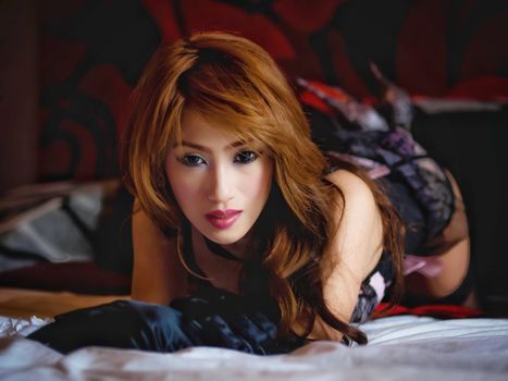 Seductive redhead woman with wavy hair posing elegantly while lying down indoors.