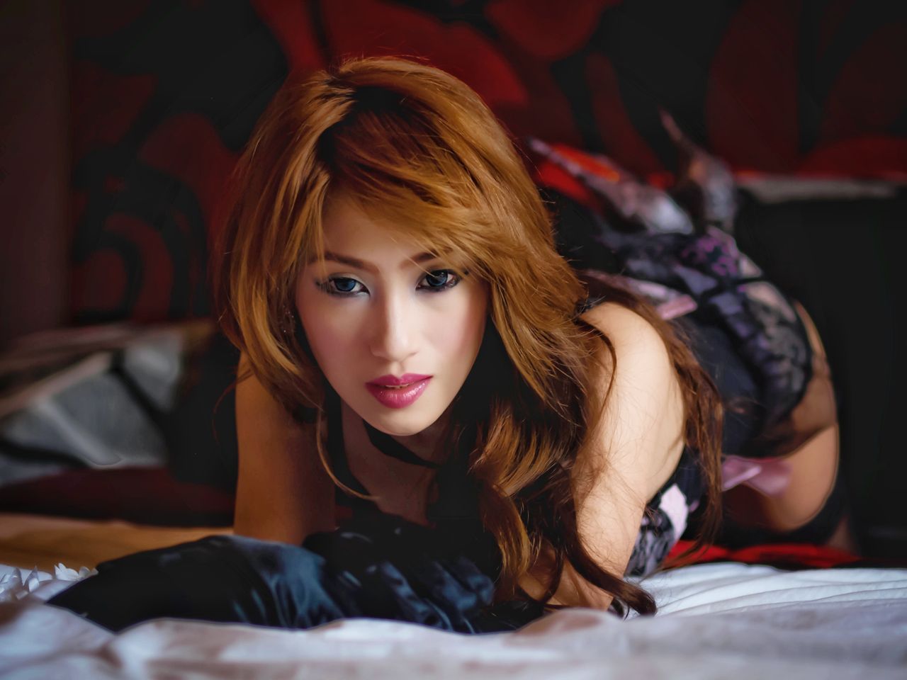 seductive redhead woman with wavy hair posing elegantly while lying do