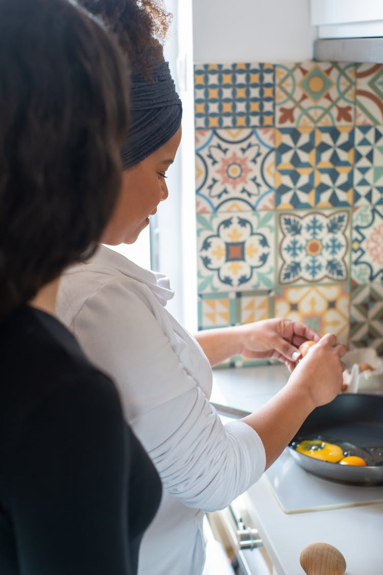 A Woman In White Long Sleeve Shirt Cooking Eggs