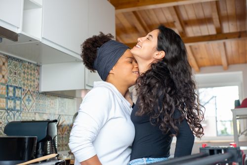 Free A loving couple shares a joyful embrace in a colorful kitchen, conveying happiness and togetherness. Stock Photo