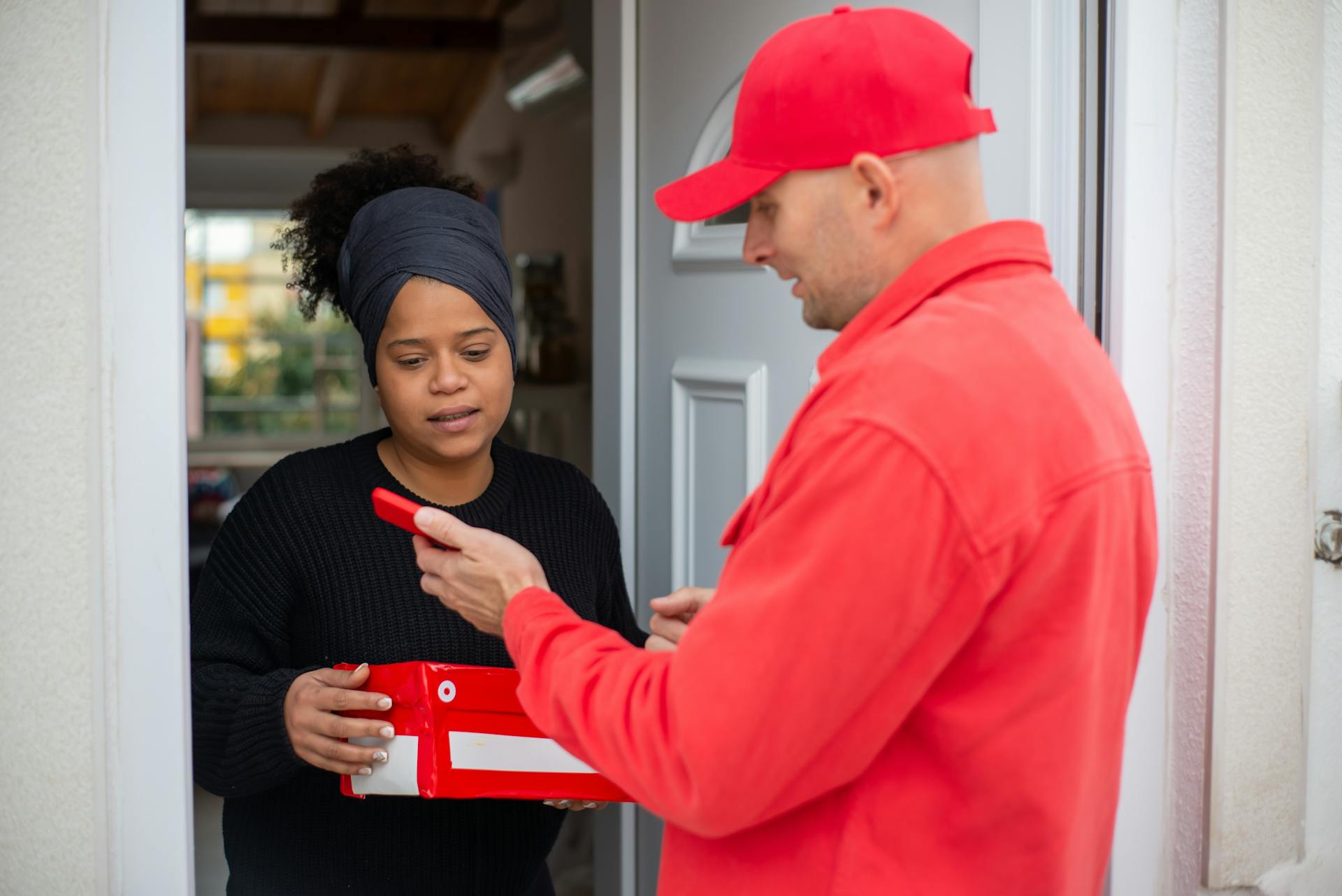 Professional delivery service with a person receiving a red package at their doorstep.