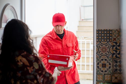 Free Man in Red Jacket Delivering a Red and White Box Stock Photo