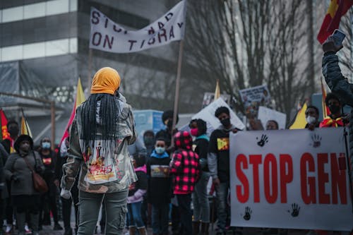 Free Group of African American people wearing medical masks standing with banners while participating in demonstration against racism on street during pandemic Stock Photo