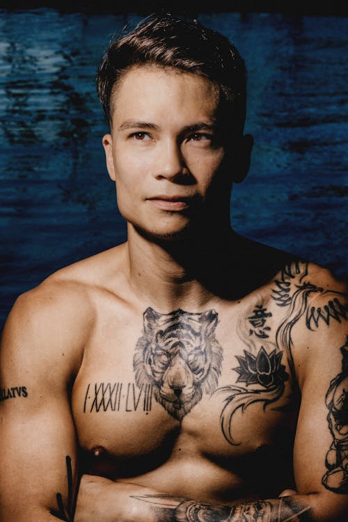 Muscular ethnic young male with tattoos near water