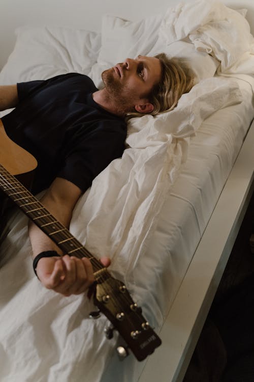 Man Lying on a Bed with a Guitar 