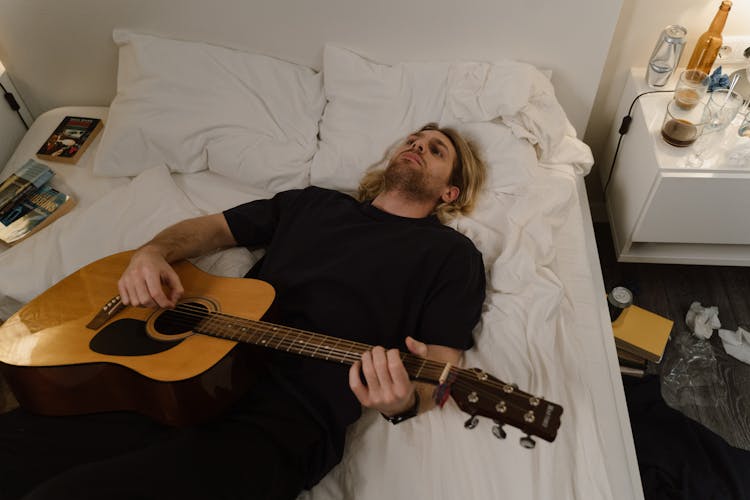 Man Lying On Bed With Guitar 