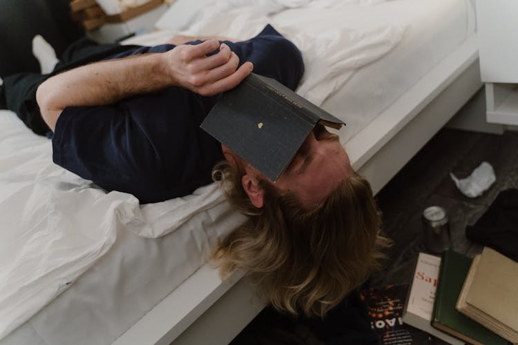 A Man Covering His Face Using A Book