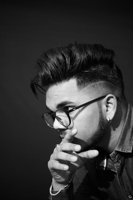 Artistic black-and-white portrait of a stylish man wearing glasses, captured in a thoughtful pose.