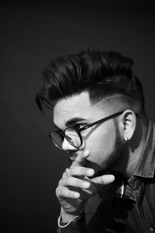 Free Artistic black-and-white portrait of a stylish man wearing glasses, captured in a thoughtful pose. Stock Photo
