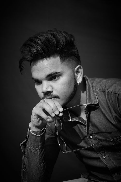 Free Black and white portrait of a thoughtful man with stylish hair, holding eyeglasses. Stock Photo