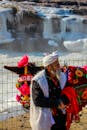 Elderly Man Standing next to Waterfall with Decorated Donkey