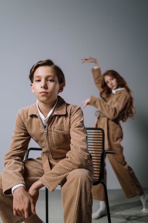 

A Boy in a Corduroy Outfit Sitting on a Chair