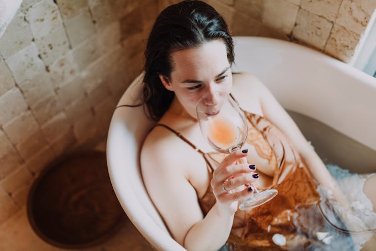 A Woman In The Bathtub Drinking A Wine