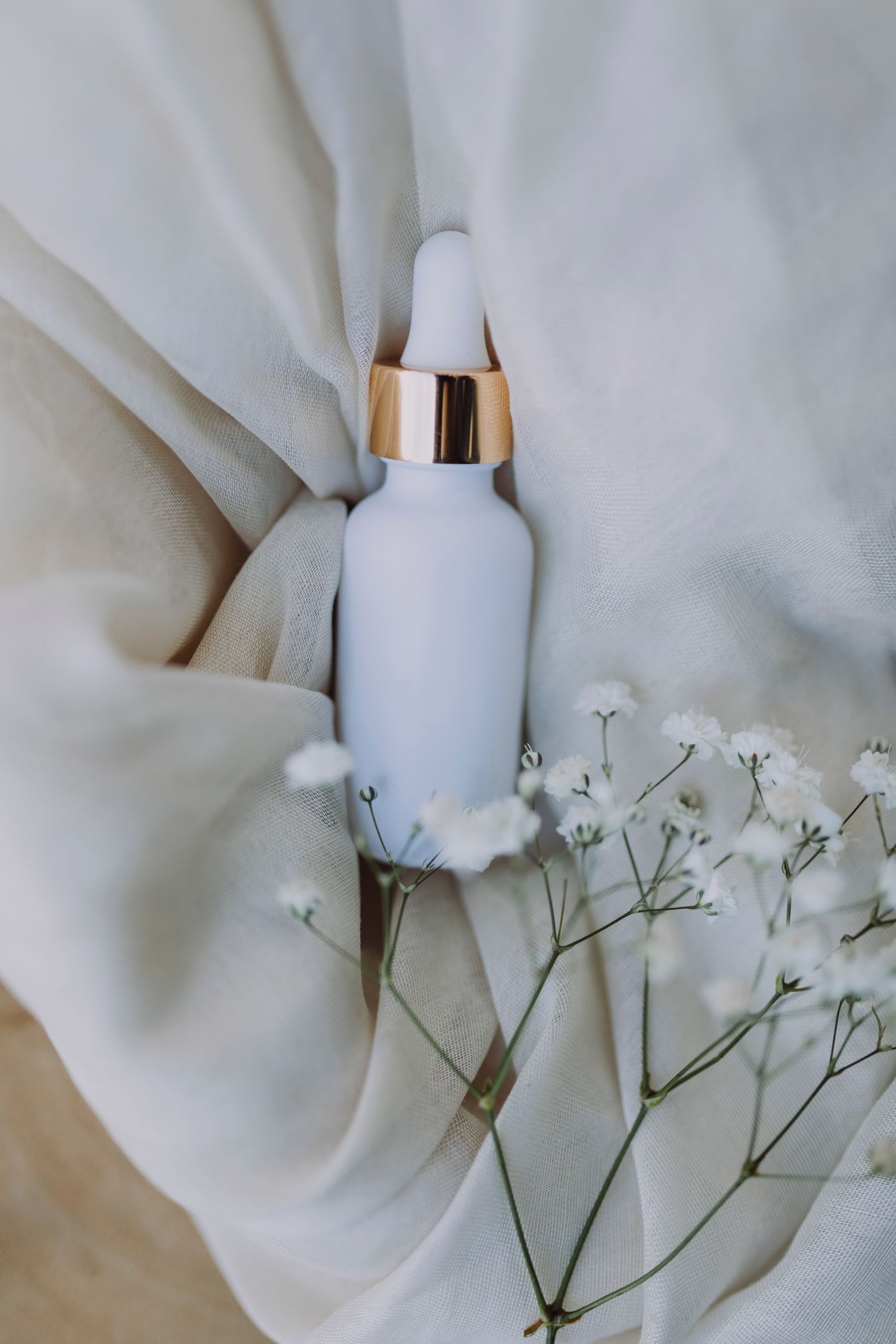 Labelled cosmetic serum bottles and skincare jar arranged on clean fabric