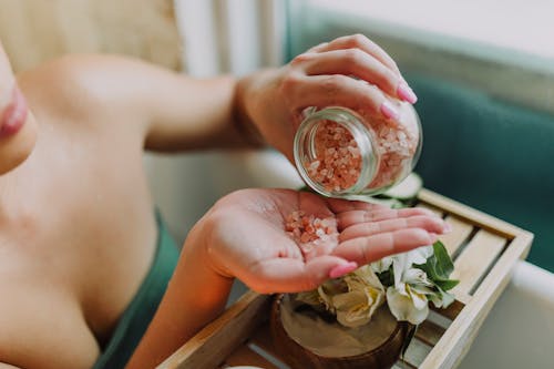 Person Holding Clear Glass Jar With Red and White Flower Petals