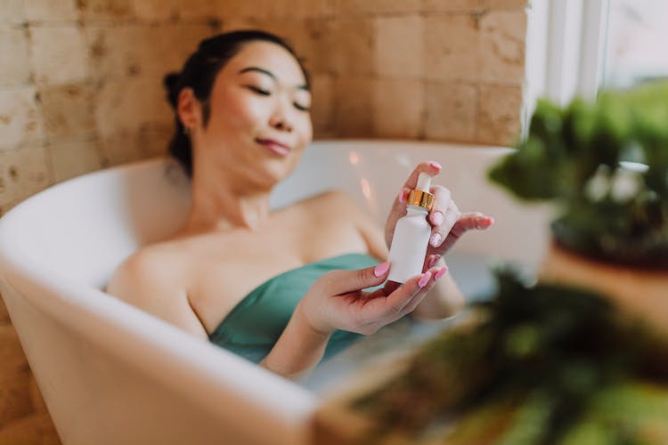 A Woman In The Bathtub Holding A Cosmetic