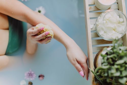 Free A relaxing bath scene featuring exfoliation with a sponge and flower petals. Stock Photo