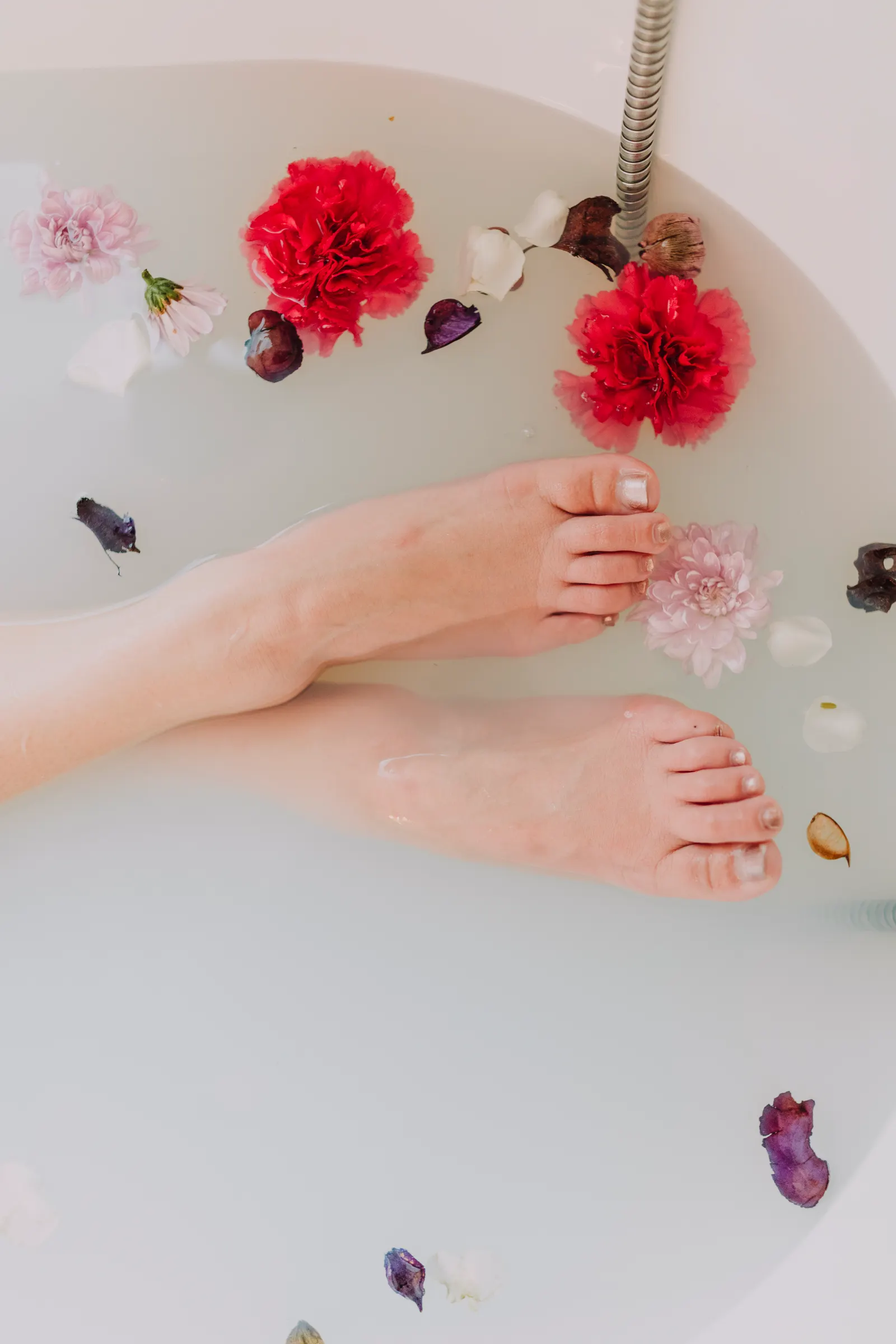 Feet soaking in a floral bath at a wellness spa.