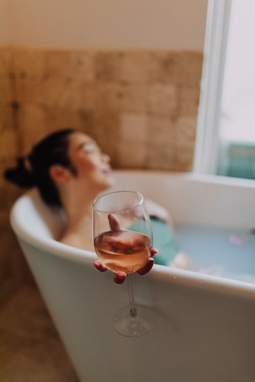 Free Woman in White Ceramic Bathtub Holding Clear Drinking Glass Stock Photo