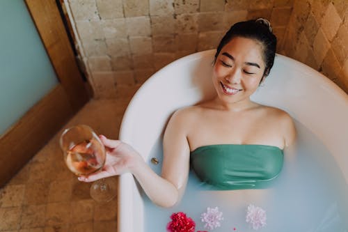 Woman Lying on Bathtub Holding a Glass of Wine