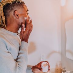 A man in a sunny bathroom working through his grooming routine