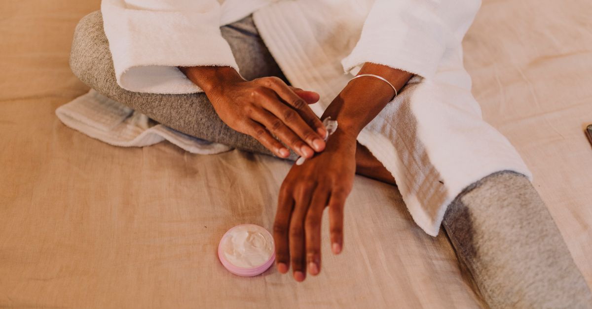 Cozy skincare session as a person applies lotion to their hands in a relaxed home setting.