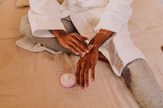 Cozy skincare session as a person applies lotion to their hands in a relaxed home setting.
