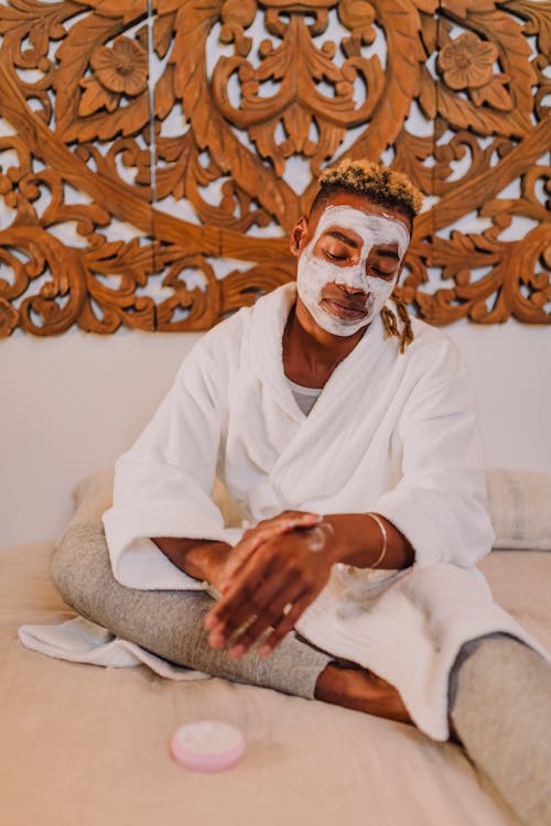 A Man with Facial Mask Applying Cream on Hand
